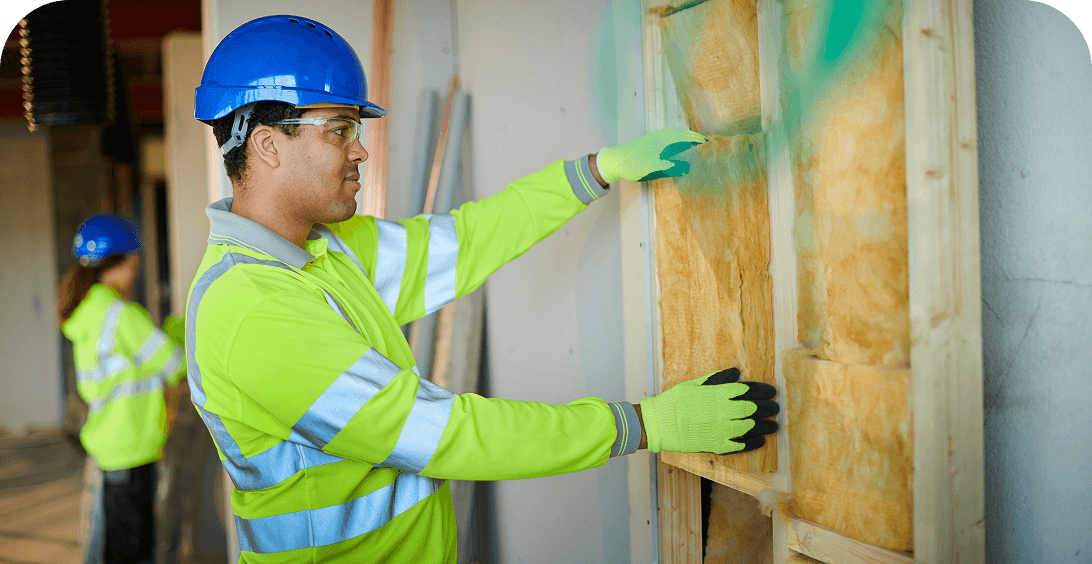Man fitting insulation in building framework