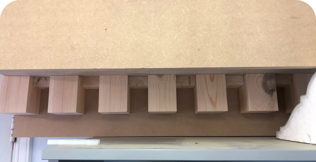 Wooden pegs beneath a wooden slab